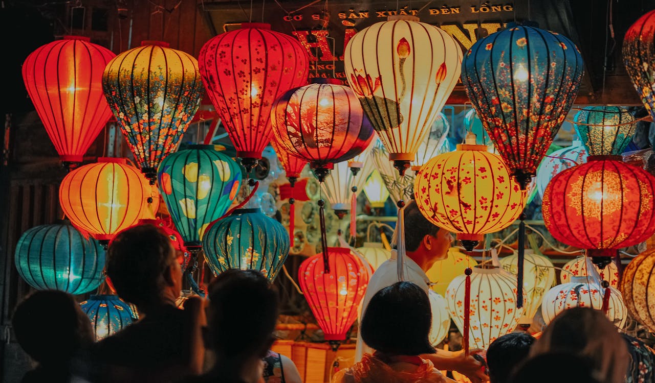 gallery-01 A lively night market scene featuring colorful illuminated paper lanterns and a crowd of people.